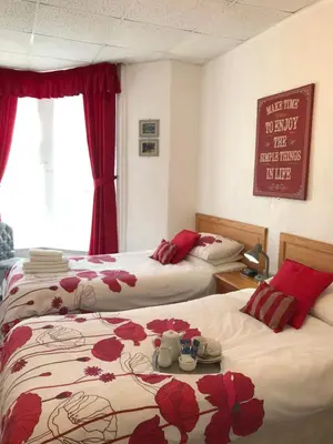 a hotel room with two beds with red flowers at The Rutland in Blackpool