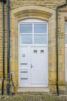 a white door on a brick building with pipes at Suite in the heart of Great Harwood in Great Harwood