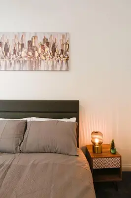 a bedroom with a bed and a table with a painting at Suite in the heart of Great Harwood in Great Harwood