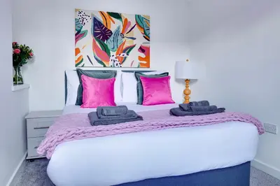 a bedroom with a white bed with pink pillows at Modern 2 bedroom flat - 15 minutes to Liverpool in Birkenhead