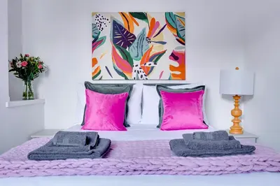 a bedroom with a bed with pink pillows and a painting at Modern 2 bedroom flat - 15 minutes to Liverpool in Birkenhead