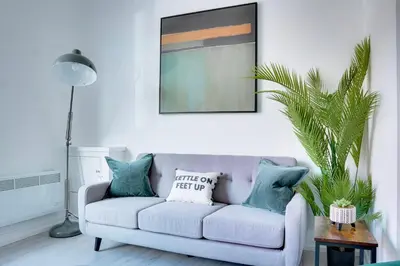 a living room with a couch and a palm tree at Modern 2 bedroom flat - 15 minutes to Liverpool in Birkenhead