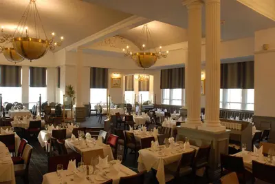 a dining room with tables and chairs and chandeliers at Imperial Hotel Blackpool in Blackpool