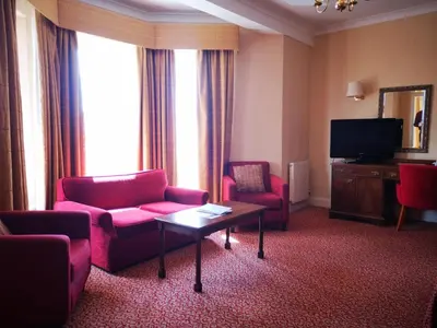 a living room with red chairs and a television at Imperial Hotel Blackpool in Blackpool