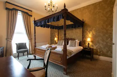 a bedroom with a canopy bed and a table and chairs at Imperial Hotel Blackpool in Blackpool