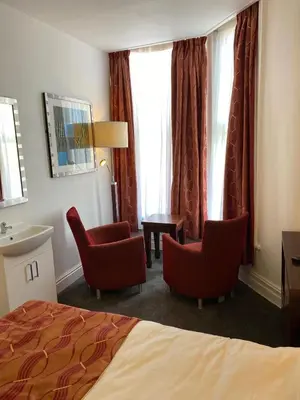 a hotel room with two chairs and a bed at The Bailey Hotel Blackpool in Blackpool
