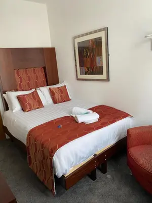 a hotel room with two beds and a chair at The Bailey Hotel Blackpool in Blackpool