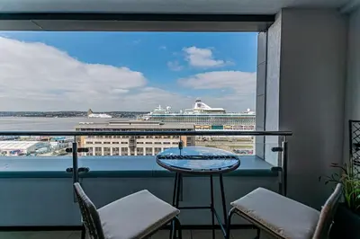a balcony with a table and chairs and a cruise ship at 1BR Apt - Balcony - River View in Liverpool