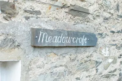 a sign on the side of a stone wall at Meadowcroft in Lindale