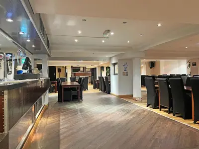 a restaurant with black chairs and a table and a bar at The President Hotel in Blackpool
