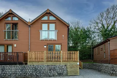 a wooden house with a porch and a fence at Lakeland Lodge 9B Arnside , Carnforth ,Lancaster , LA61BH in Carnforth
