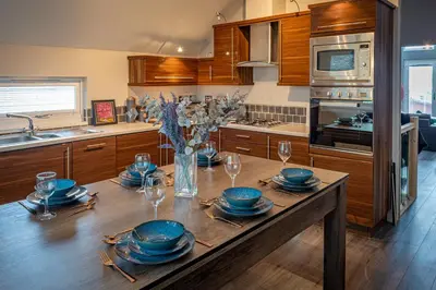 a kitchen with a table with plates and glasses on it at Lakeland Lodge 9B Arnside , Carnforth ,Lancaster , LA61BH in Carnforth