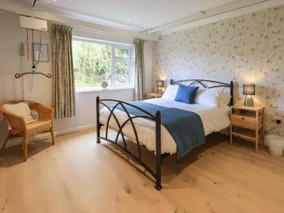 a bedroom with a bed and a chair and a window at Pembroke in Grange Over Sands