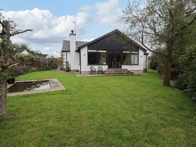 a house with a green yard in front of it at Pembroke in Grange Over Sands