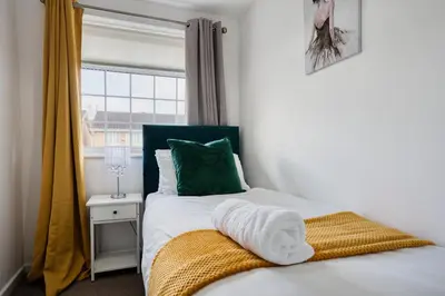 a bedroom with a bed with a green pillow and a window at LIVERPOOL HOME with FREE PARKING in West Derby