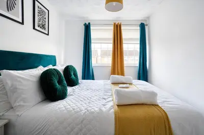 a bedroom with a large white bed with blue curtains at LIVERPOOL HOME with FREE PARKING in West Derby