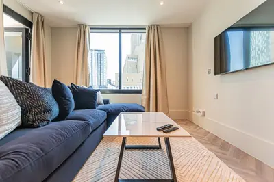 a living room with a blue couch and a glass table at 1 Bed Apt - Balcony - City View - Great Location in Liverpool