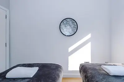 a white room with a couch and a clock on the wall at Stylish Apartment located in the City Centre of Liverpool - Web-exclusive offers at a-kapartments in Liverpool