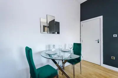 a dining room with a glass table and green chairs at Stylish Apartment located in the City Centre of Liverpool - Web-exclusive offers at a-kapartments in Liverpool
