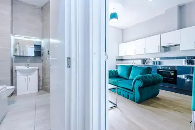 a living room with a blue couch and a kitchen at Stylish Apartment located in the City Centre of Liverpool - Web-exclusive offers at a-kapartments in Liverpool