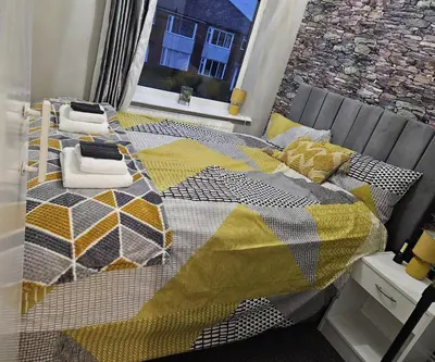 a bed with a yellow and gray quilt on it at Clifton House, For Holidays, Contractors, Relocation, Work, Etc, Free Parking and Wifi in Preston
