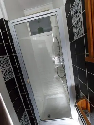 a glass shower in a bathroom with black tiles at Captivating 1-Bed Apartment in Blackpool in Blackpool