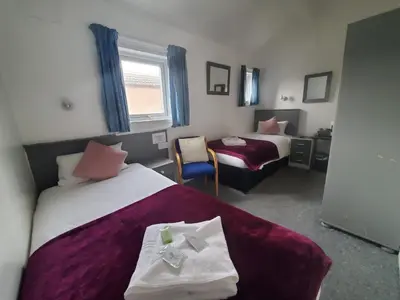 a hotel room with two beds and a chair at Brooklyn Hotel in Blackpool