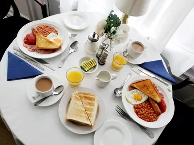 a table with plates of breakfast foods and cups of coffee at Brooklyn Hotel in Blackpool