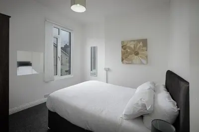 a white bedroom with a bed and two windows at Lovely Home in Blackpool For You in Blackpool