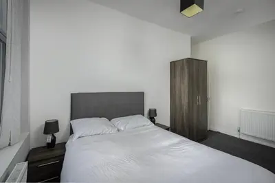 a bedroom with a white bed and a wooden cabinet at Lovely Home in Blackpool For You in Blackpool