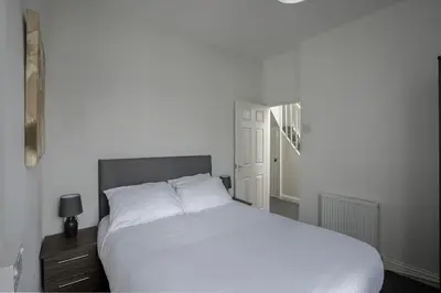 a bedroom with a white bed with a night stand and a window at Lovely Home in Blackpool For You in Blackpool