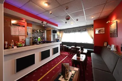 a bar in a restaurant with red walls at The Wilton International in Blackpool