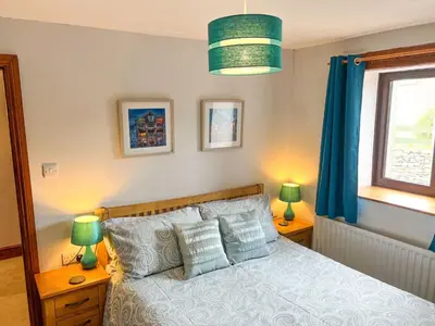 a bedroom with a bed with blue curtains and two lamps at The Hayloft, Broughton Beck, near Ulverston budget friendly accommodation close to a beach and Windermere in Spark Bridge