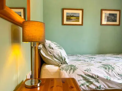 a bedroom with a bed and a table with a lamp at The Hayloft, Broughton Beck, near Ulverston budget friendly accommodation close to a beach and Windermere in Spark Bridge