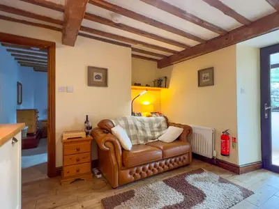 a living room with a leather couch and a table at The Stable, Broughton Beck, a ground floor cottage close to a beach and Windermere in Spark Bridge