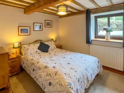a bedroom with a bed and a window at The Stable, Broughton Beck, a ground floor cottage close to a beach and Windermere in Spark Bridge