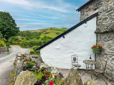 a stone building with a table and a chair at The Stable, Broughton Beck, a ground floor cottage close to a beach and Windermere in Spark Bridge