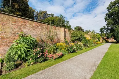 a brick wall with a garden of flowers at Lytham Hall Gate House in Lytham St Annes