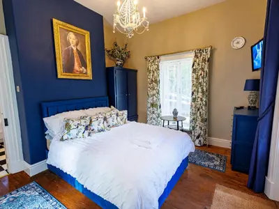 a blue bedroom with a bed and a chandelier at Lytham Hall Gate House in Lytham St Annes