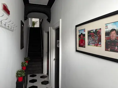 a hallway with a staircase with pictures on the wall at Anfield Abode - ENTIRE LFC THEMED HOUSE - Sleeps 6 in Liverpool