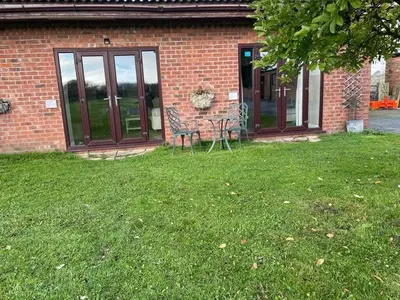 a bench in a yard next to a brick building at Another Place in Formby