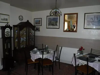 a dining room with a table and chairs and a clock at Camelot Hotel - Couples Only in Blackpool
