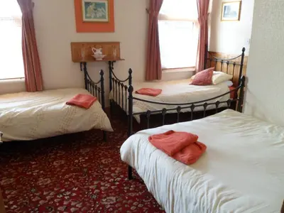 a room with three beds with red towels on them at Camelot Hotel - Couples Only in Blackpool