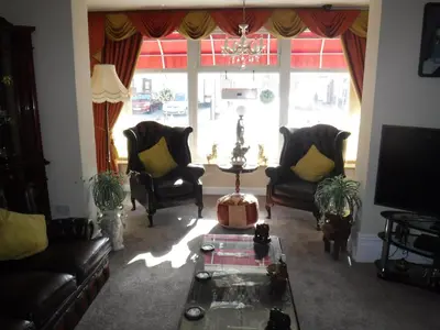 a living room with couches and a table and a large window at Camelot Hotel - Couples Only in Blackpool