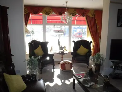 a living room with chairs and a table and a window at Camelot Hotel - Couples Only in Blackpool