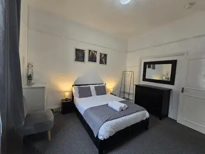 a bedroom with a bed and a chair and a mirror at Cheerful Home near Preston train station & Uclan in Preston