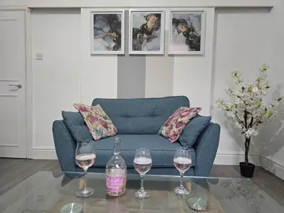 a living room with a blue couch and two glasses of wine at Cheerful Home near Preston train station & Uclan in Preston