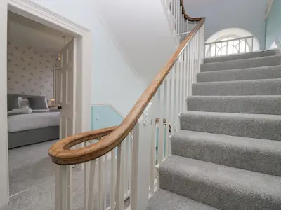 a staircase in a house with a wooden hand rail at Holmere Bank in Carnforth