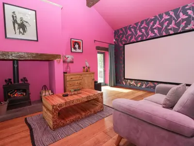 a living room with pink walls and a large screen at Holmere Bank in Carnforth