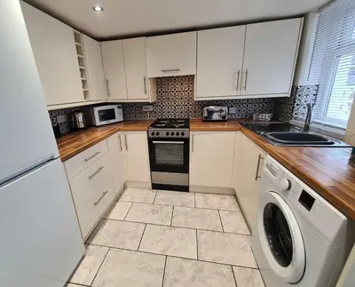 a kitchen with white cabinets and a washer at Lancaster 2 Bedroom Characterful House - with Wifi in Lancaster